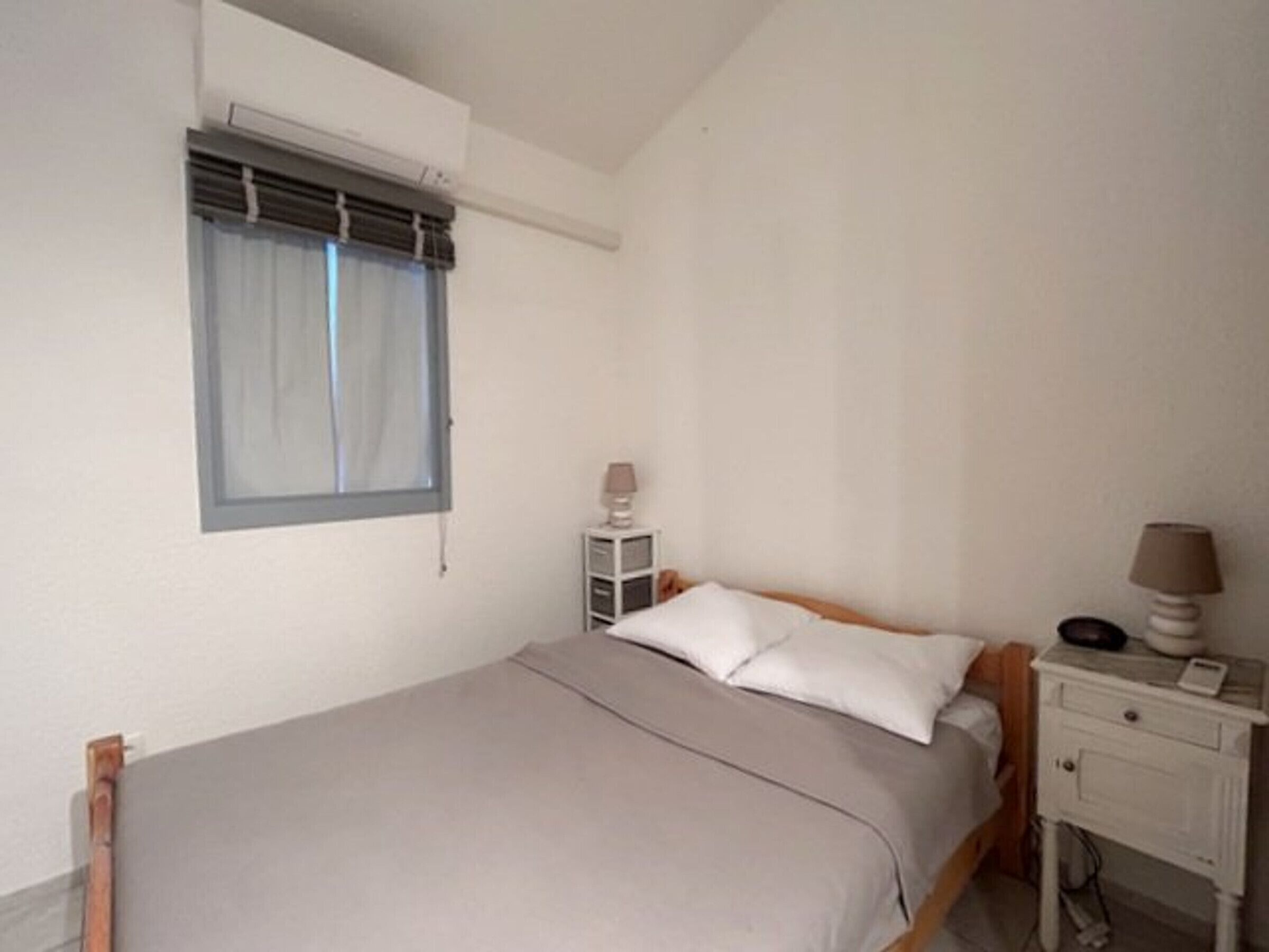A bedroom with a bed, a bedside table, a lamp, and a window with curtains.