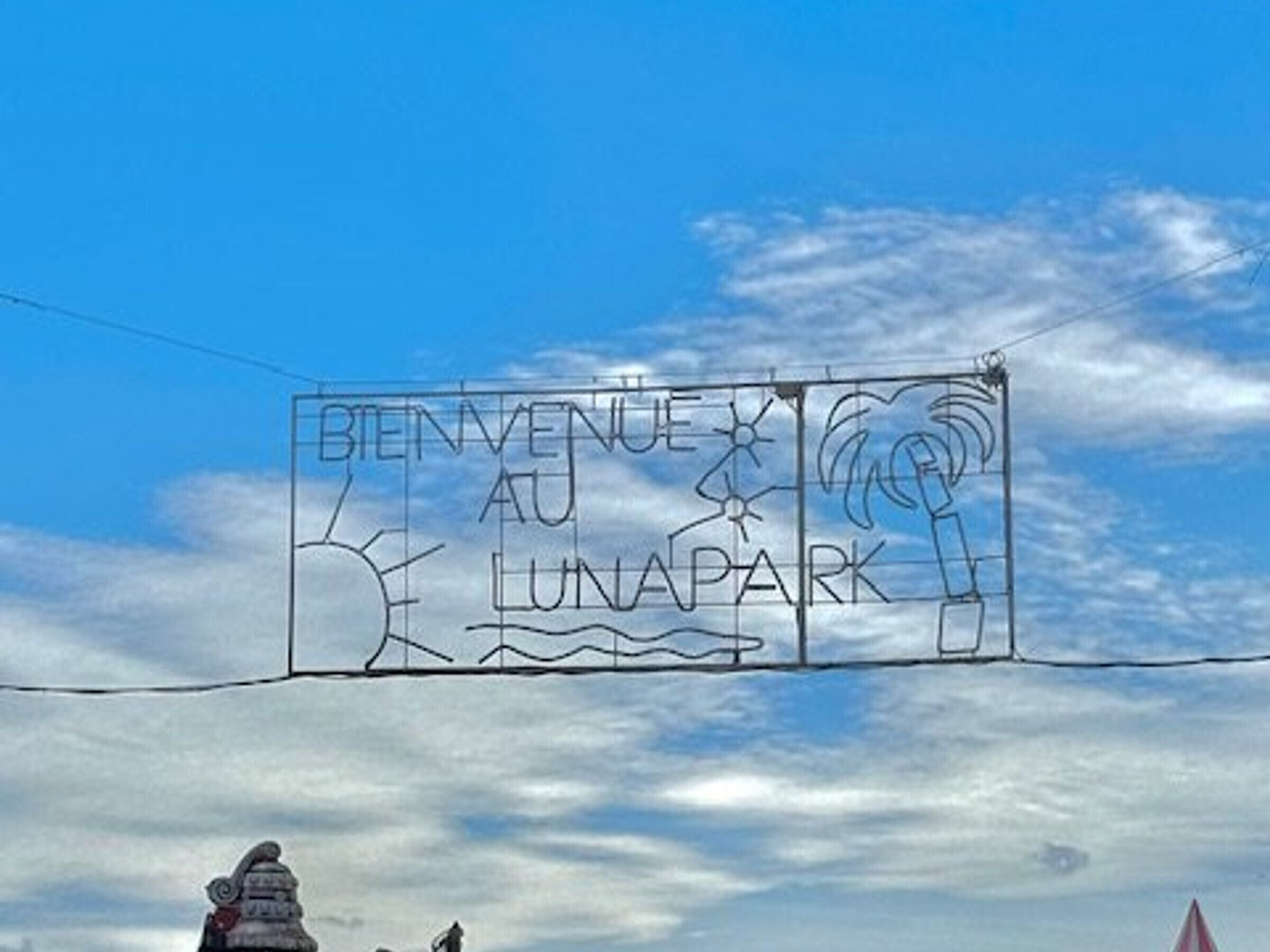 En skylt med texten ”BIENVENUE AU LUNAPARK” mot en klarblå himmel.
