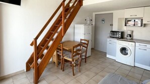 A compact kitchen with a washing machine, a microwave, and a coffee maker. - Charming T2 with mezzanine and parking in Le Barcarès (Le Barcarès)