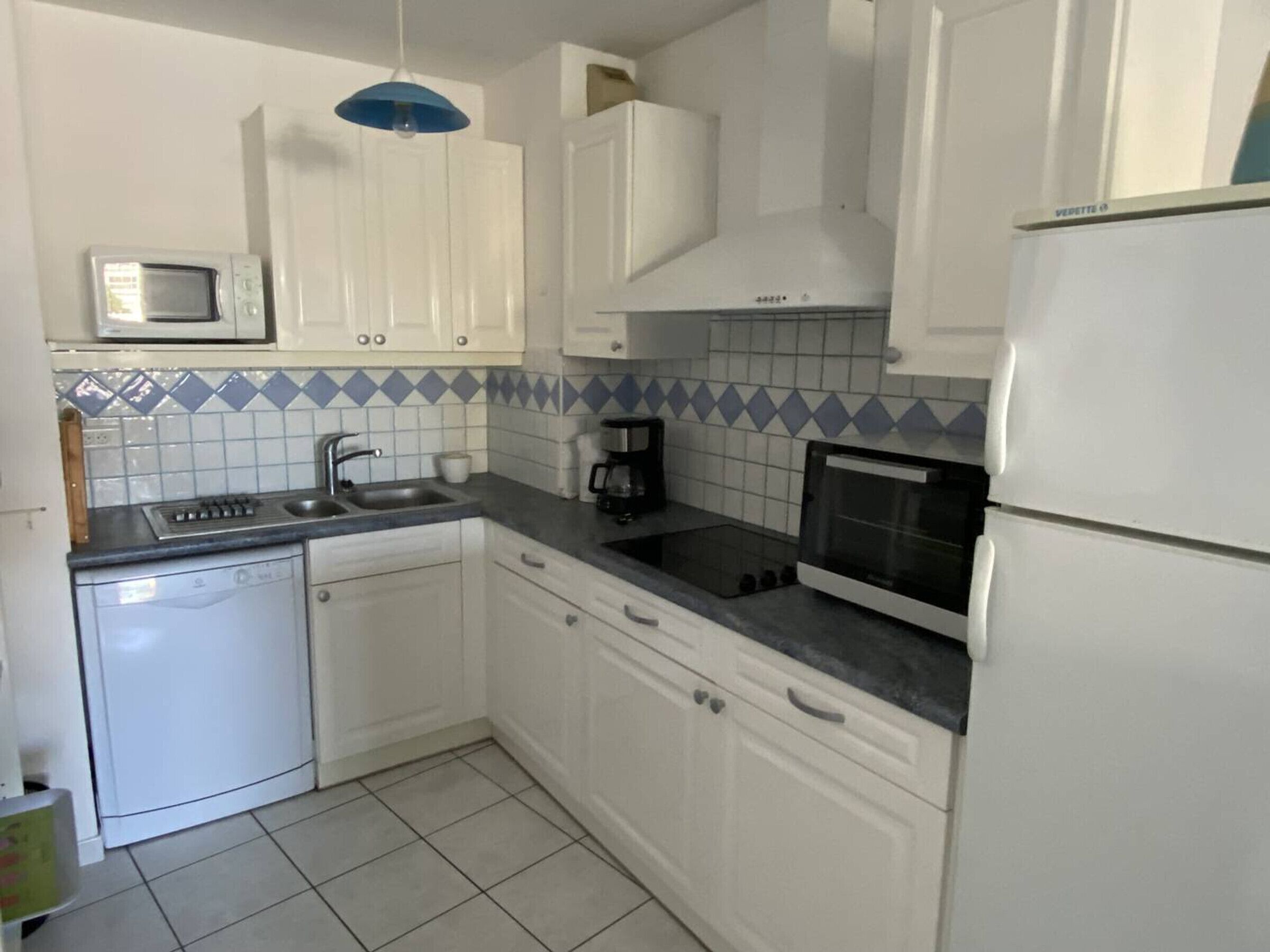 A kitchen with white cabinets, a microwave, a coffee maker, and a refrigerator.