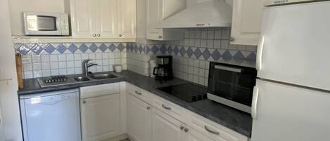 A kitchen with white cabinets, a microwave, a coffee maker, and a refrigerator.