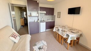 Un espacio habitable compacto con kitchenette, comedor y sofá.