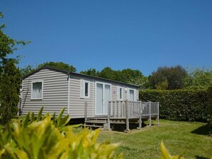A single-story mobile home with a porch, surrounded by greenery. - Mobile Home in Bénodet - 3 Bedrooms, Terrace (Bénodet)