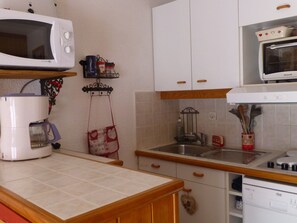 Eine Küche mit weißen Schränken, einer Mikrowelle, einer Kaffeemaschine und einem Herd.