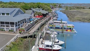 A waterfront restaurant with outdoor seating and a docked boat. - Almost Heaven on Sunset-Pool-Walk to Beach (Murrells Inlet)
