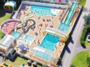 Luchtbeeld van een waterpark met verschillende zwembaden, glijbanen en een grote waterglijbaan.