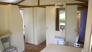 A room with a wooden ceiling, a white table, and a chair. There is a door leading to another room. - Cozy chalet with terrace in Bénodet (Bénodet)