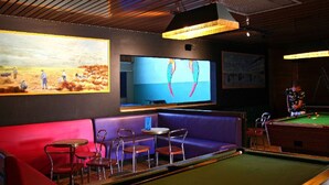 A pool table with a green felt surface, surrounded by a red and purple seating area with metal chairs. - Cozy chalet with terrace in Bénodet (Bénodet)