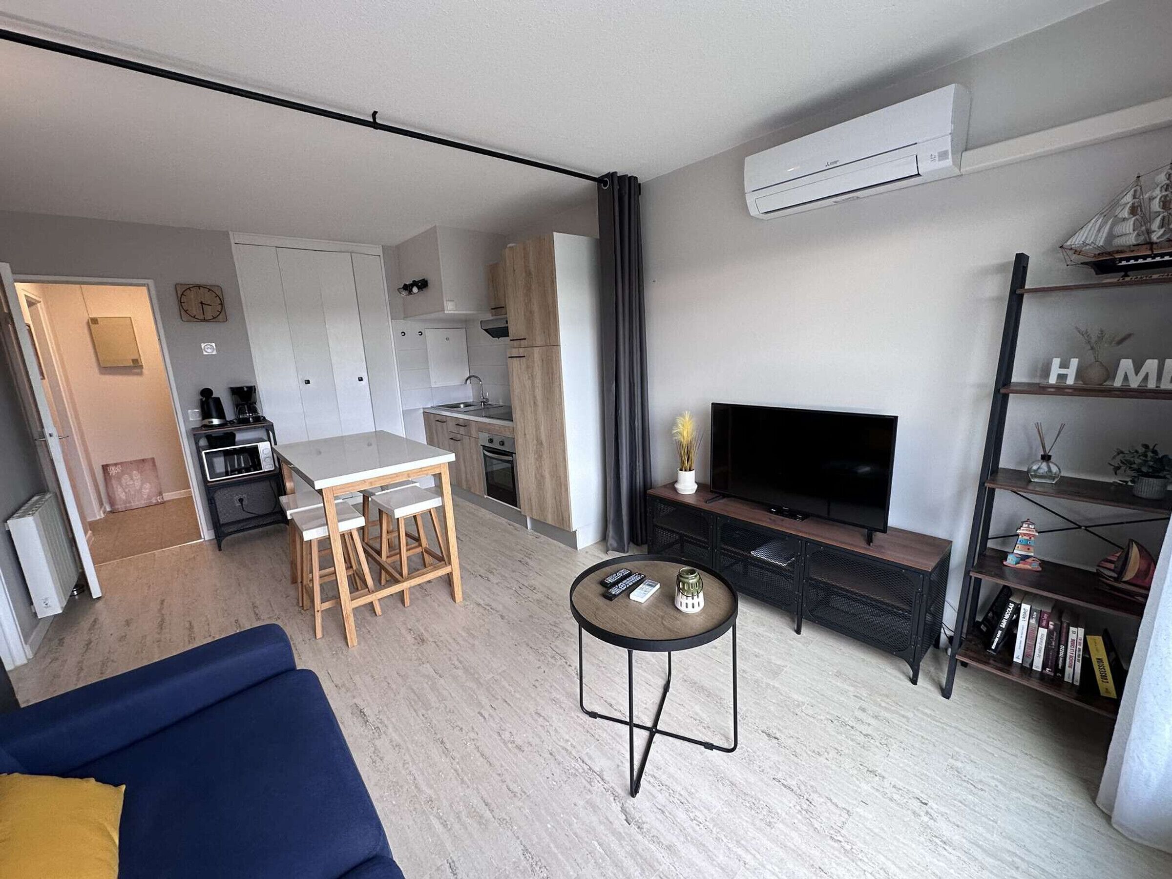 A modern living room with a sofa, a coffee table, a TV, and a bookshelf.