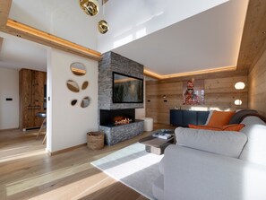 Ein modernes Wohnzimmer mit Kamin aus Stein, einem Flachbildfernseher und einer Couch.