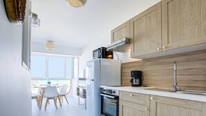 A modern kitchen with wooden cabinets, a built-in oven, and a coffee maker. - Canet Beach modern renovated T2, near sea (Canet-en-Roussillon)