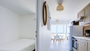 A compact, modern kitchen with a dining area, a bed, and a large window providing natural light. - Canet Beach modern renovated T2, near sea (Canet-en-Roussillon)