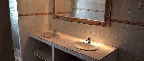 A bathroom with two sinks, a mirror, and a towel rack.