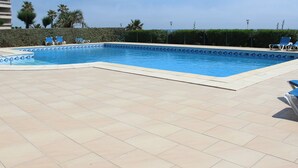 A rectangular swimming pool with a tiled deck, surrounded by palm trees and a clear sky. - Luxurious air-conditioned apartment with great view and secure parking (Canet-Plage)