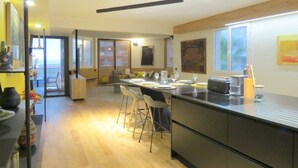 A modern kitchen with a central island, bar stools, and a dining area. - Luxurious air-conditioned apartment with great view and secure parking (Canet-Plage)