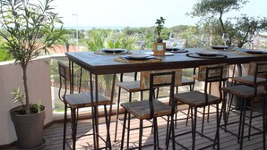 An outdoor dining area with a wooden table and chairs, set against a scenic backdrop. - Luxurious air-conditioned apartment with great view and secure parking (Canet-Plage)