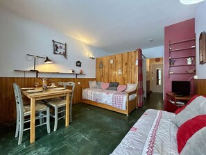 A cozy room with a wooden bed, a dining table with chairs, and a TV. - Ski-In Studio for 4 pers. with Parking (Le Dévoluy)