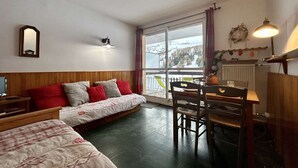 A cozy room with a bed, a desk, and a chair. There is a window with a view of a snowy landscape. - Ski-In Studio for 4 pers. with Parking (Le Dévoluy)