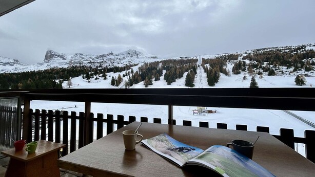 A wooden table with a book and a mug on it, overlooking a snowy mountain landscape with a forest and a ski lift. - Ski-In Studio for 4 pers. with Parking (Le Dévoluy)