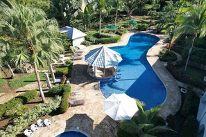 A resort with a large swimming pool, palm trees, and sun loungers. - Surrounded by nature with A/C (Quepos)