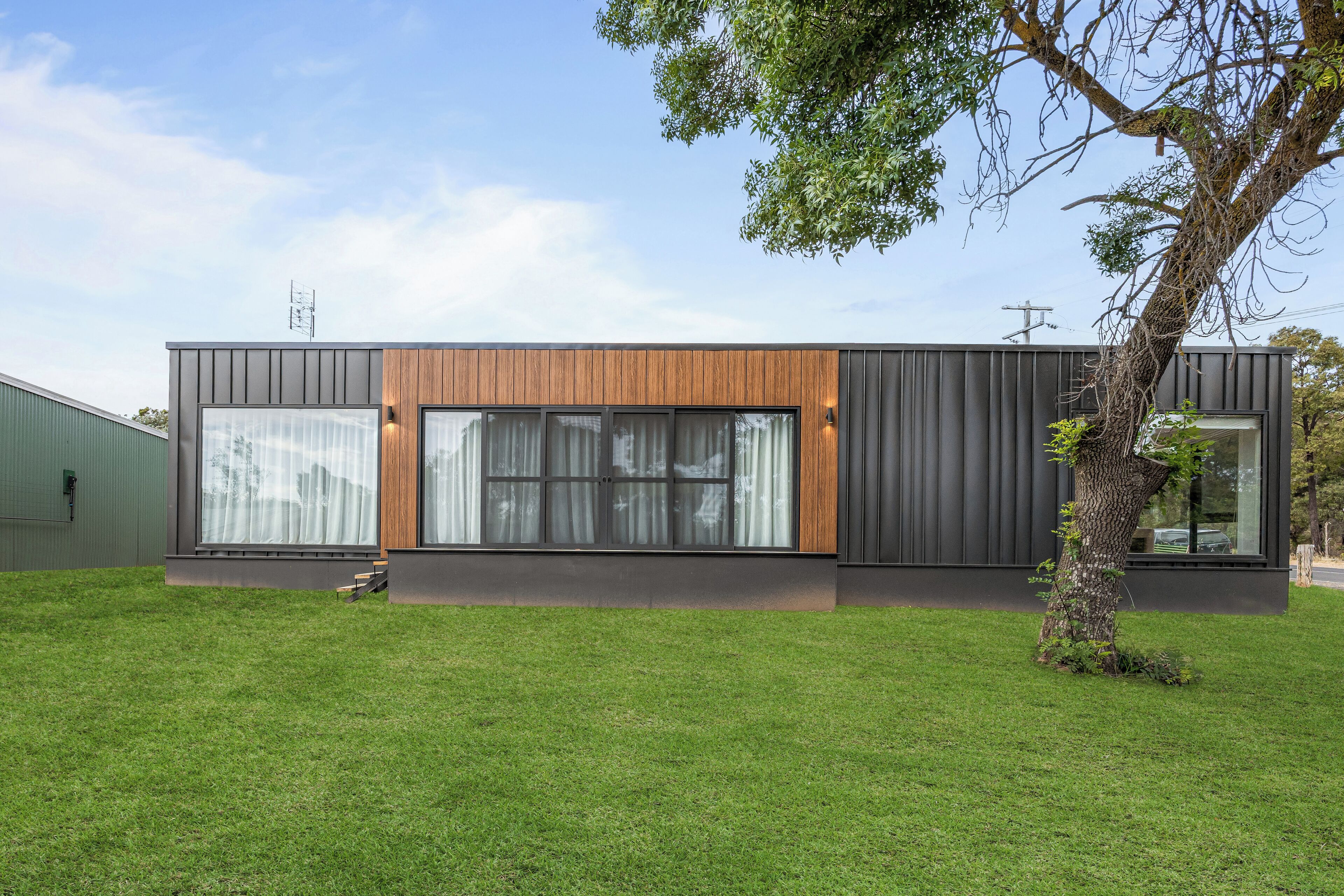 Un edificio moderno con amplios ventanales y un detalle en paneles de madera.