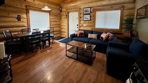 A log cabin interior with a dining area, sofa, and fireplace. - Cozy cabin and a beautiful waterfront view from your deck. The perfect getaway! (Lac Le Jeune)