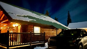 A log cabin with a wooden porch and a vehicle parked in front. - Cozy cabin and a beautiful waterfront view from your deck. The perfect getaway! (Lac Le Jeune)