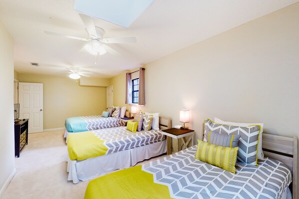 A bedroom with two beds, a ceiling fan, a bedside table with a lamp, and a door. - Dog-friendly Home With Central AC, Washer/dryer & Spacious Backyard - Near Beach (St. Simons Island)