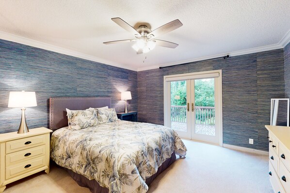 A bedroom with a bed, nightstands, a ceiling fan, and a sliding glass door to a balcony. - Dog-friendly Home With Central AC, Washer/dryer & Spacious Backyard - Near Beach (St. Simons Island)