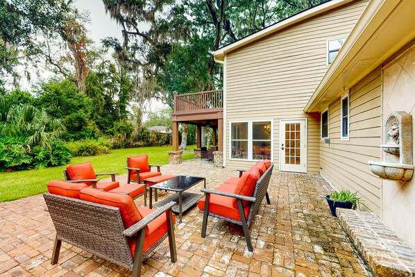 An outdoor patio with wicker furniture and a brick floor. - Dog-friendly Home With Central AC, Washer/dryer & Spacious Backyard - Near Beach (St. Simons Island)