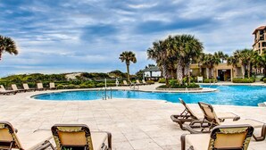 Una piscina con sillas de descanso y palmeras.
