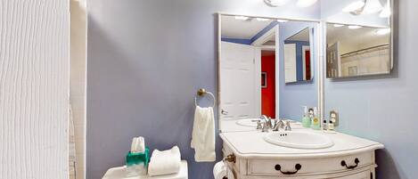 A bathroom with a white sink, a mirror, and a toilet.