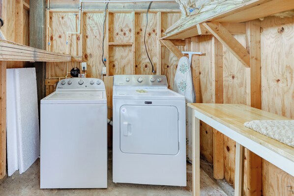 A laundry room with two stacked washers and dryers, wooden walls, and a wooden table with a white towel. - Dog-friendly Home With Beach Access & Deck - Snowbirds Welcome (St. Augustine)