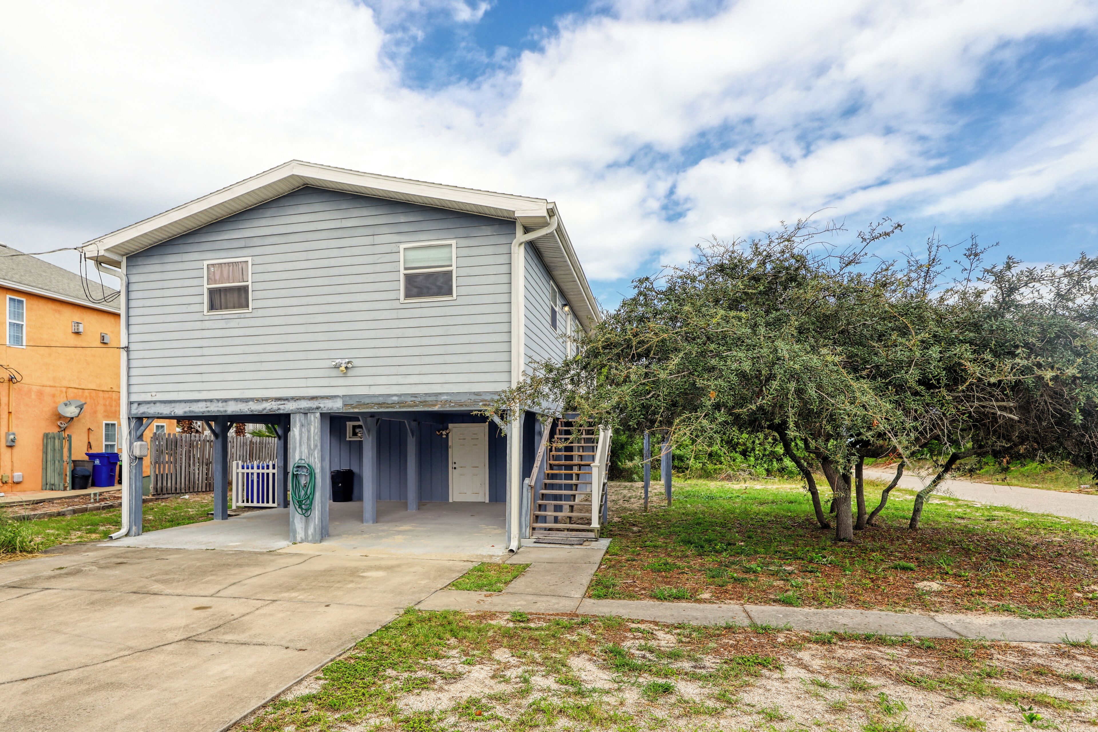 A two-story house with a covered front porch and a small staircase leading to the entrance.