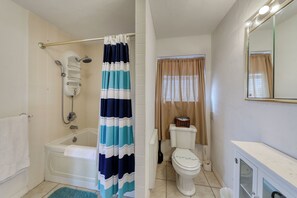 Un baño con bañera, inodoro y cortina de ducha.