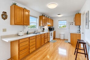 A modern kitchen with wooden cabinets, a white countertop, a stove, and a sink. - Dog-friendly Home With Beach Access & Deck - Snowbirds Welcome (St. Augustine)