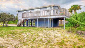 A two-story house with a balcony, surrounded by vegetation and a cloudy sky. - Dog-friendly Home With Beach Access & Deck - Snowbirds Welcome (St. Augustine)