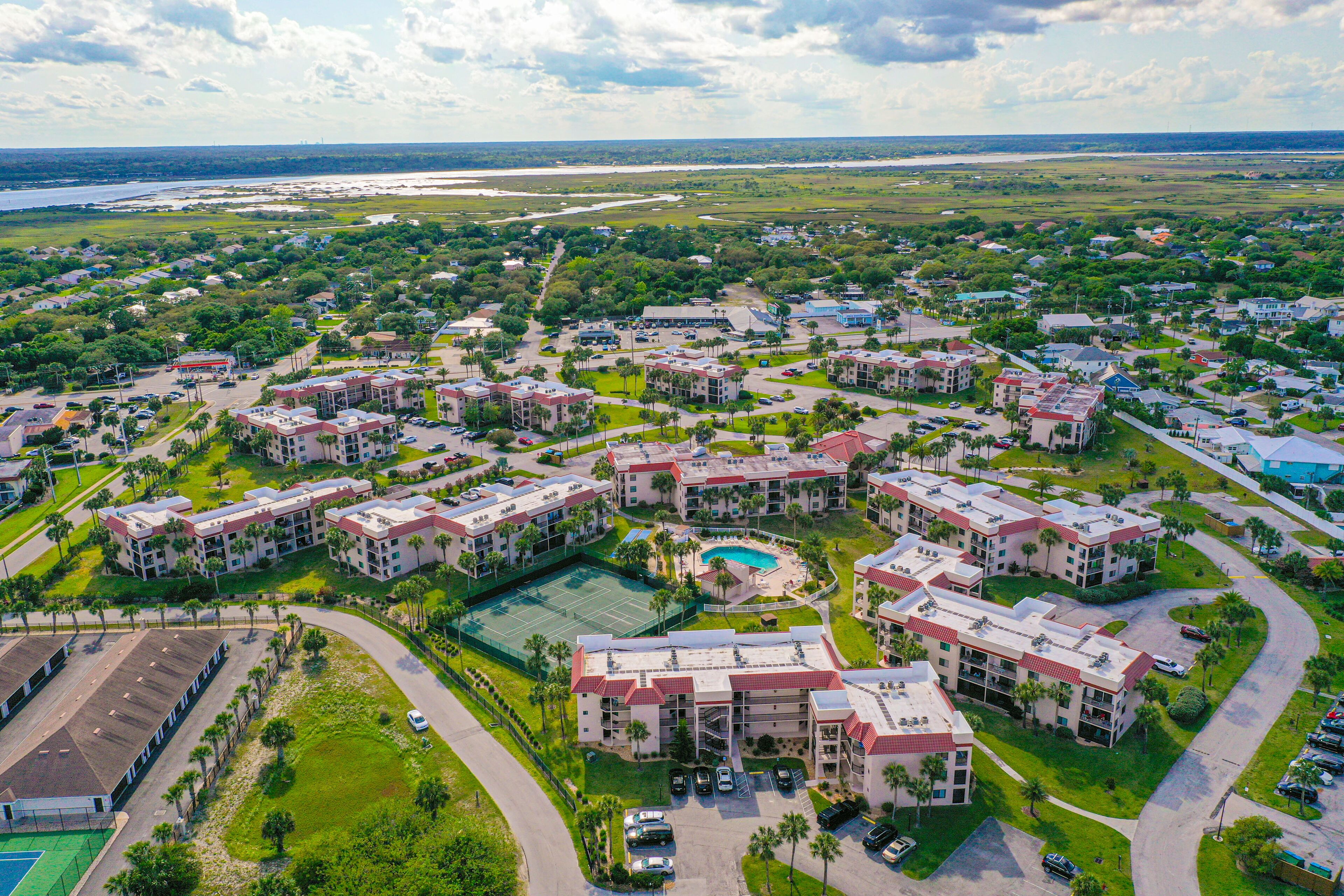 A residential area with multiple apartment buildings, a tennis court, and a swimming pool.