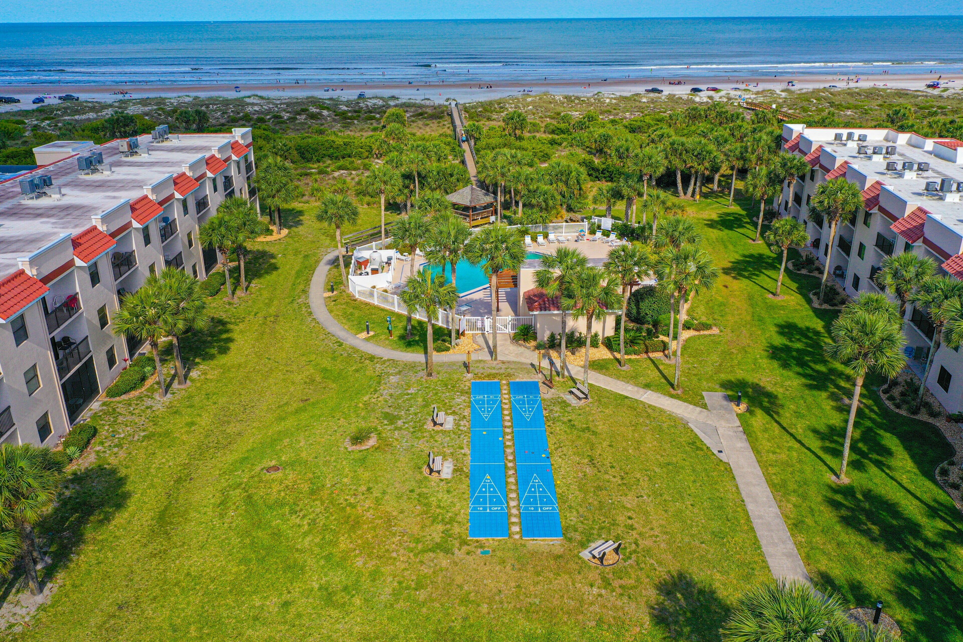 Un resort con piscina, palmeras y vistas a la playa.