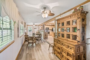 A spacious dining area with a wooden dining table and chairs, a wooden cabinet with glass doors, and ceiling fans. - Dog-friendly Home With High-speed Wifi, Washer/dryer, Central AC, & Adult Bikes (St. Augustine)