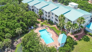 Ein mehrstöckiges Hotel mit Swimmingpool und Palmen.