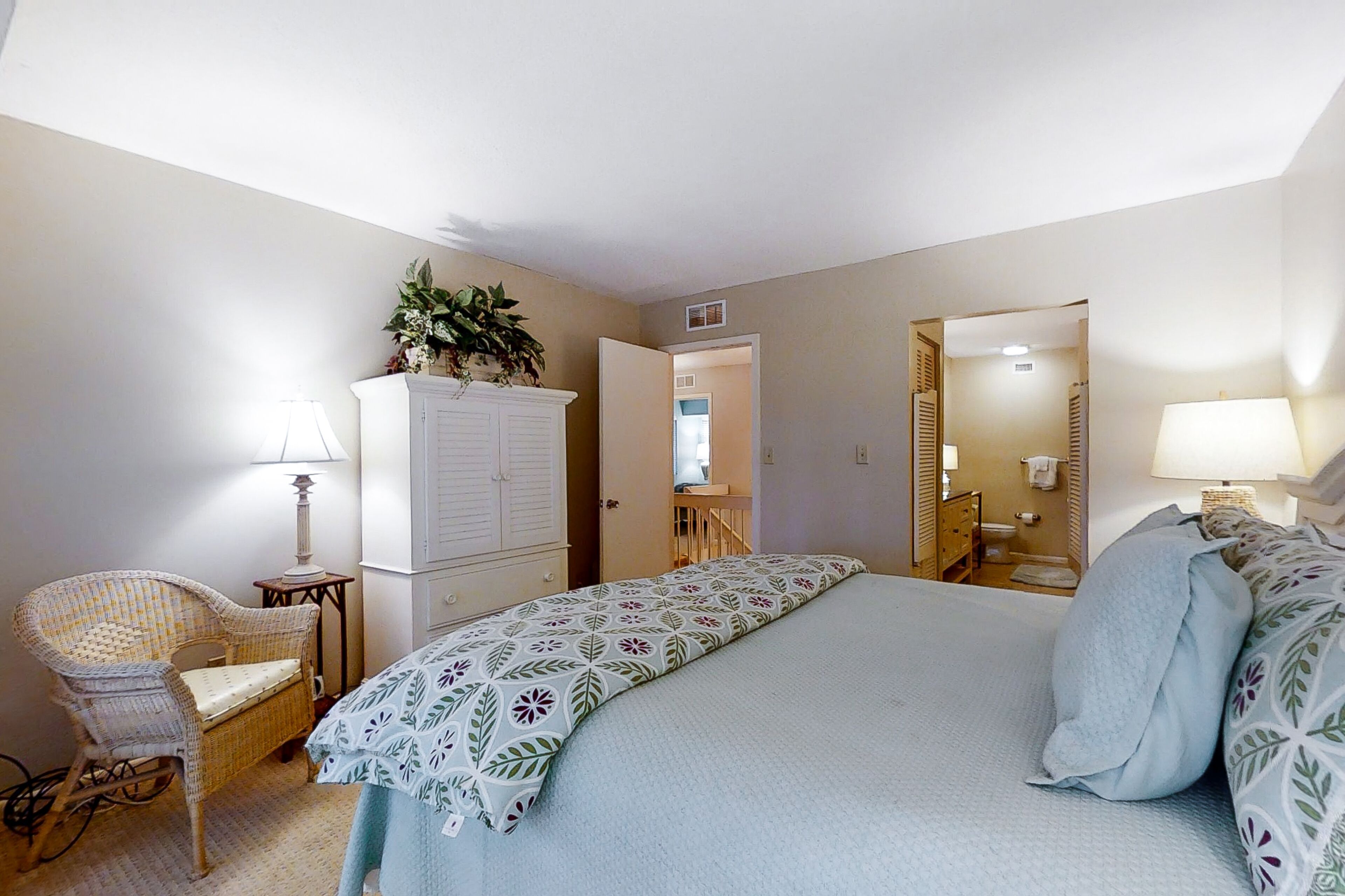A bedroom with a bed, a chair, a wardrobe, and a mirror.