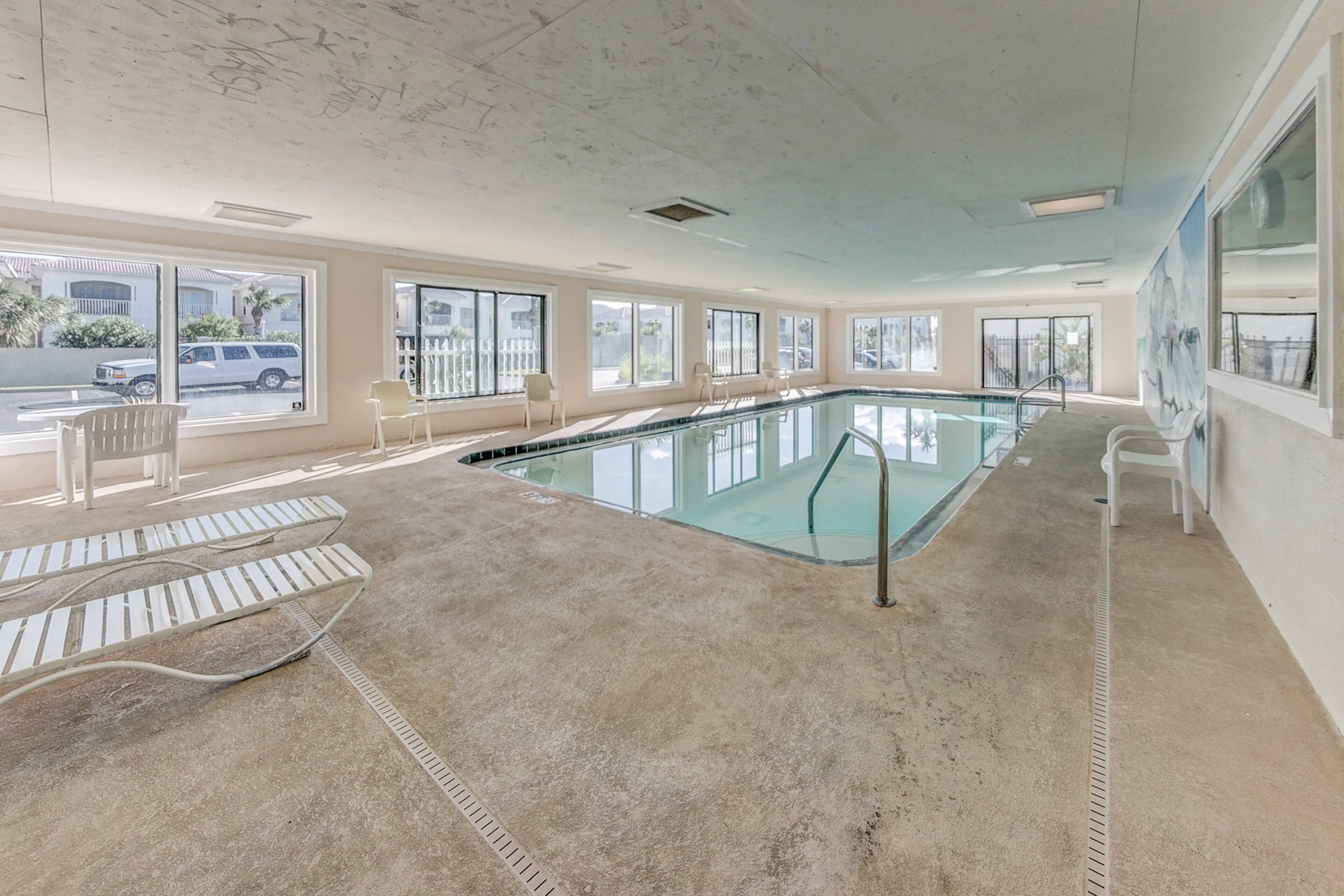 Une piscine avec des parois en verre transparent, un sol en béton et une vue sur la rue.