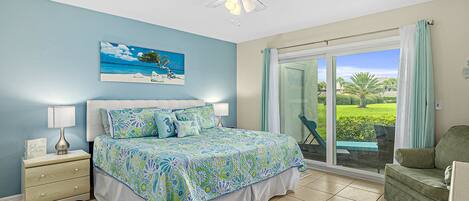 A bedroom with a bed, nightstand, lamp, and a painting of a beach scene.