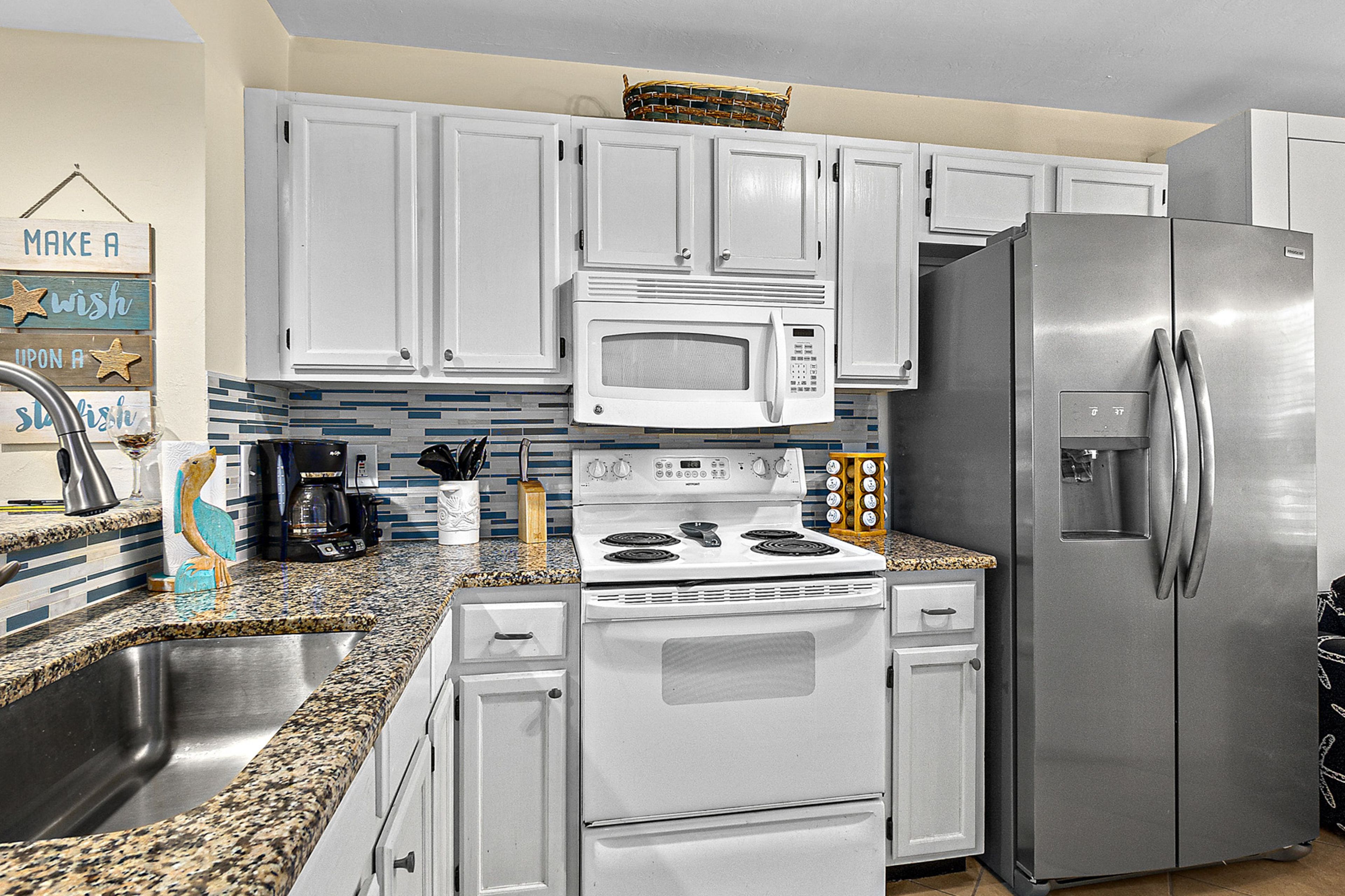 A kitchen with white cabinets, a stainless steel refrigerator, a microwave, and a stove.