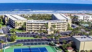 A hotel with multiple floors, a parking lot, and a tennis court. - Garden-level Condo With Patio, 2 Pools, Gym, Tennis & Sauna - Steps to the Beach (St. Augustine)