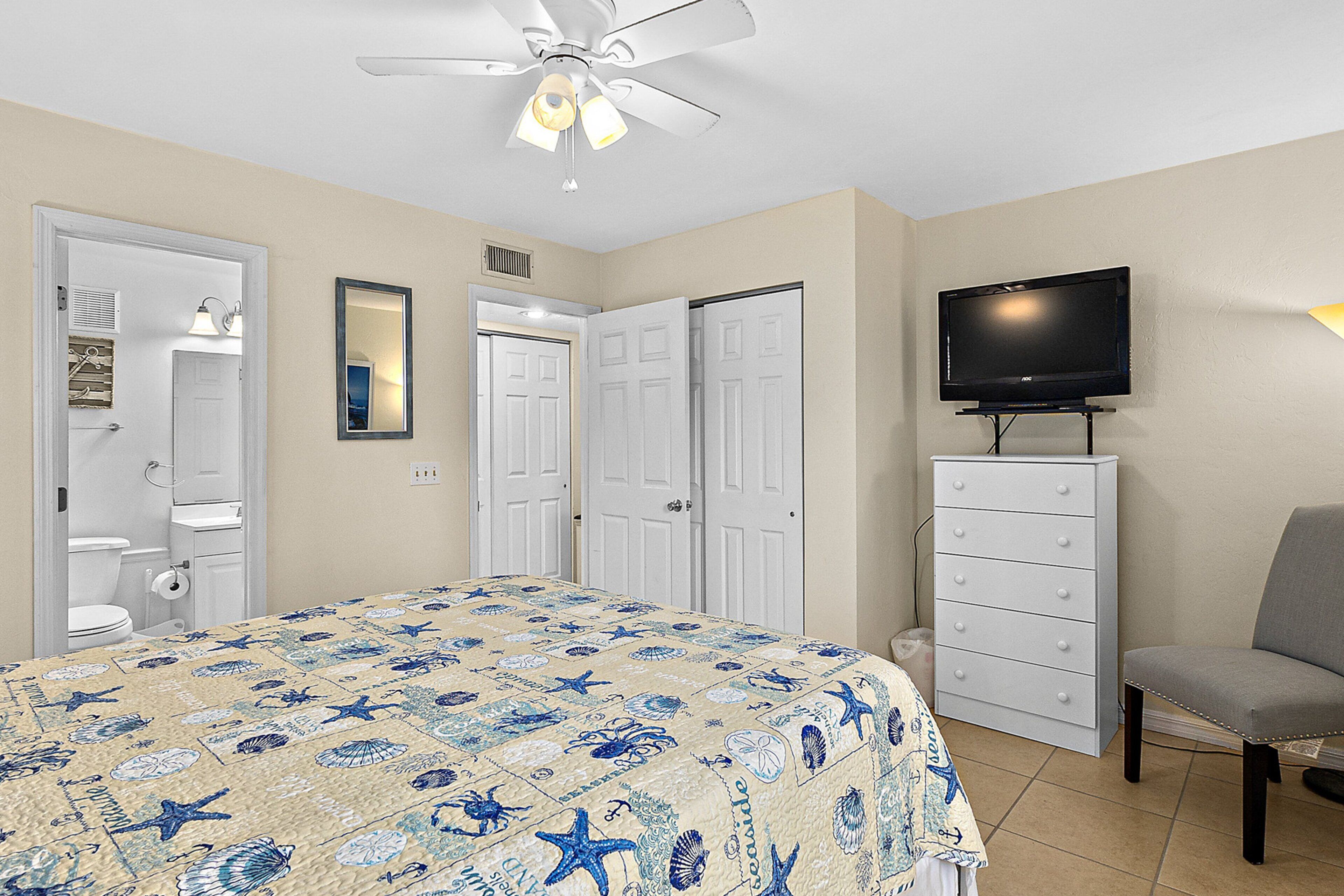 A bedroom with a bed, a television, a dresser, and a chair.