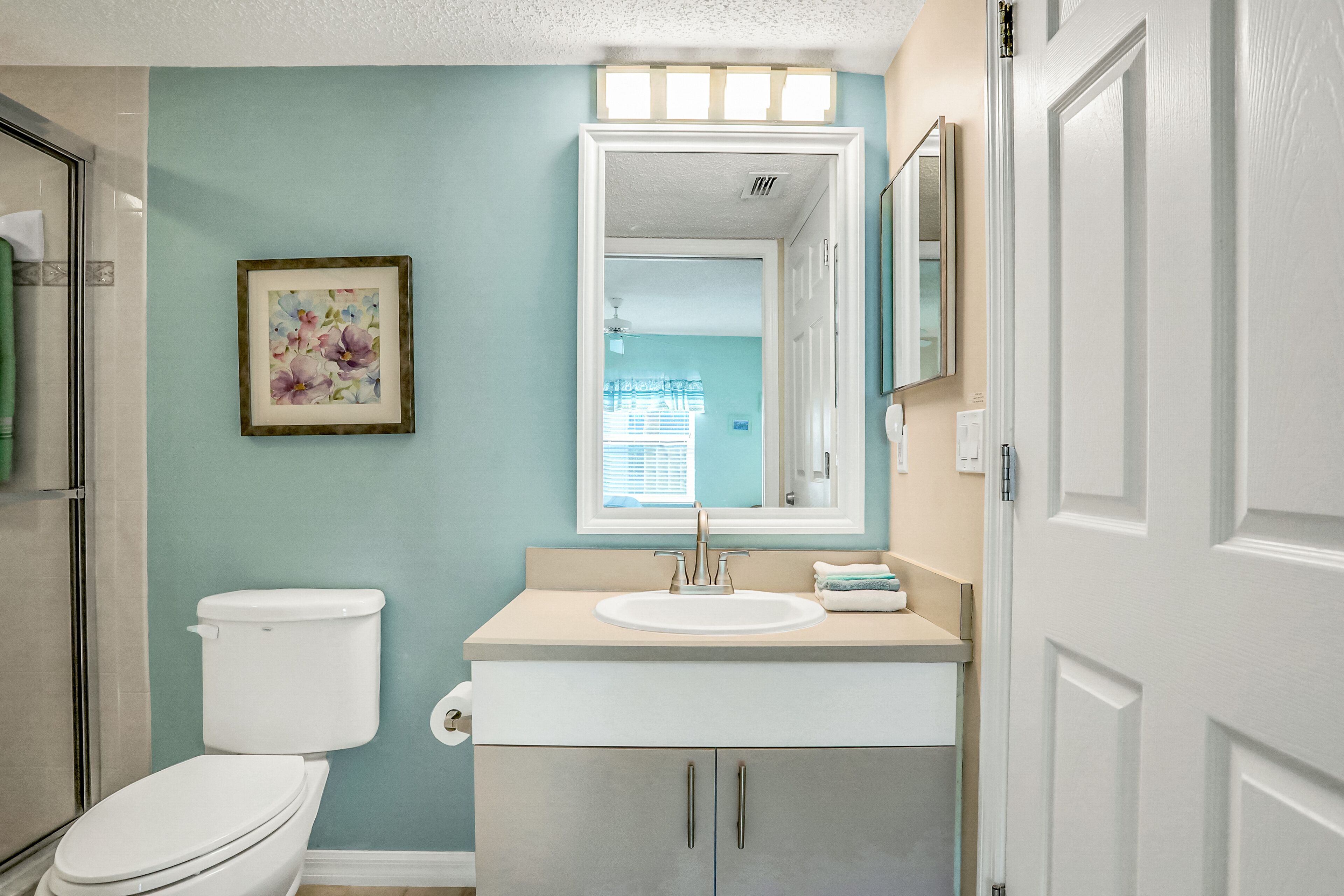 A bathroom with a toilet, sink, and cabinet.
