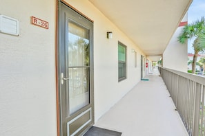A corridor with a door labeled "R-26," a window, and a balcony with a railing. - Freedom By The Sea II With Ocean Views, 2 Pools, Tennis & gym - Steps to Beach (St. Augustine)