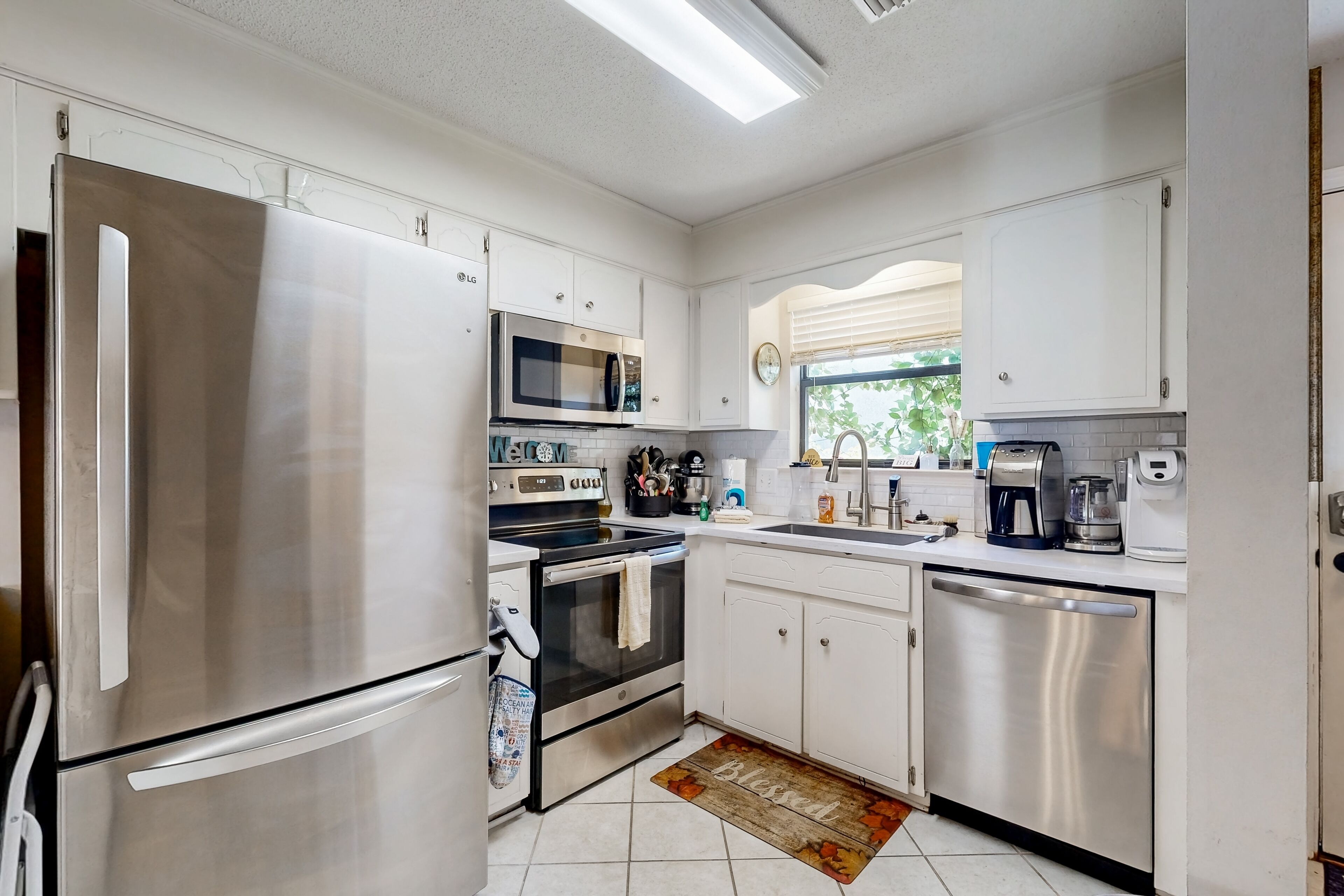 Una cocina moderna con electrodomésticos de acero inoxidable, armarios blancos y salpicadero de azulejos.